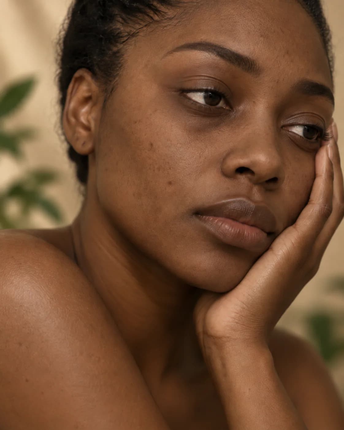 Femme noire au teint terne reposant sa joue dans sa main